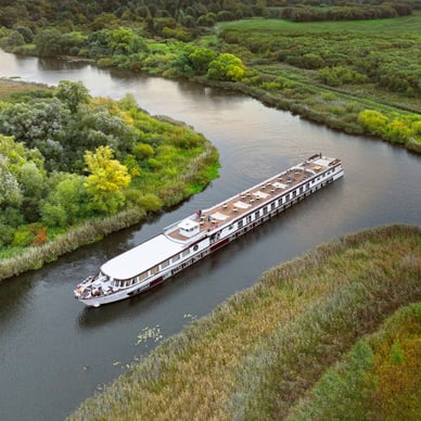 Das Flussschiff Excellence Coral gleitet auf der Peene bei Demmin durch üppige Flusslandschaft, aufgenommen aus der Luft.