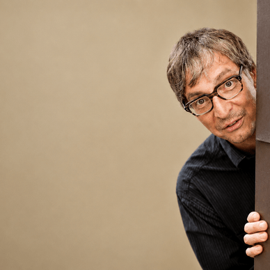 Eine Person mit Brille schaut um eine Ecke.
