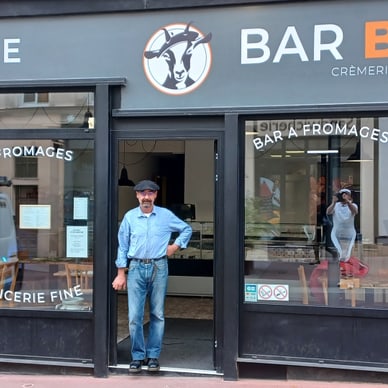 Mann steht vor einer Fromagerie namens Bar Bickett.