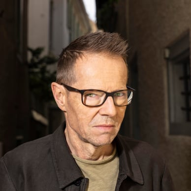 Person mit Brille steht in einem schmalen Durchgang.
