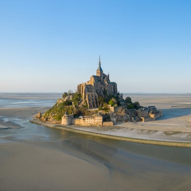 Luftaufnahme einer mittelalterlichen Insel mit umliegendem Sand und Wasser bei Ebbe.