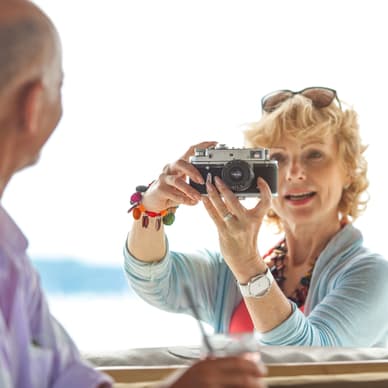 Person hält Kamera und fotografiert andere Person an einem sonnigen Ort.