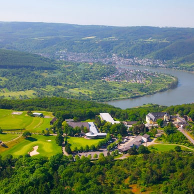 goflclub-jakobsberg.jpg Luftaufnahme von grüner Landschaft mit Fluss und Gebäuden.