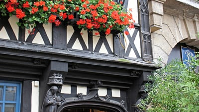 twerenbold_42296.jpg Historische Fachwerkfassade mit Blumen und dekorativem Schild.