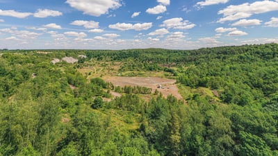 twerenbold_83281.jpg Landschaftsansicht mit bewaldeten Hügeln unter blauem Himmel.