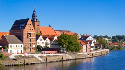 twerenbold_84168.jpg Historische Gebäude am Flussufer mit blauem Himmel.