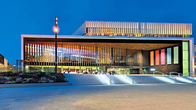 Moderne Architektur mit beleuchtetem Gebäude und Treppen bei Nacht.