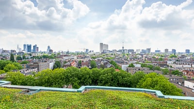 Stadtpanorama mit grüner Dachterrasse und Wolken am Himmel.
