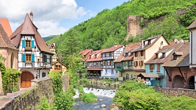 kaysersberg.jpg Malerisches Dorf mit Fachwerkhäusern entlang eines Baches.