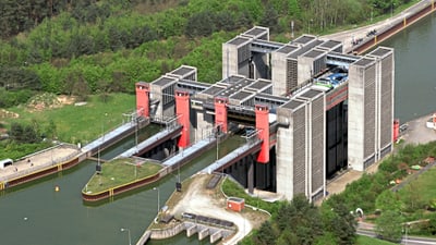 schiffshebewerk-scharnebeck.jpg Luftaufnahme eines grossen Schiffshebewerks umgeben von Wasser und Bäumen.