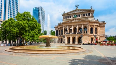 Opernhaus mit Brunnen und Hochhäusern im Hintergrund bei Tag.