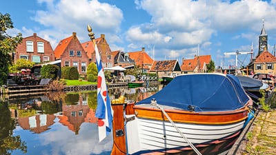 twerenbold_46456.jpg Hafen mit Booten und traditionellen Häusern bei blauem Himmel.