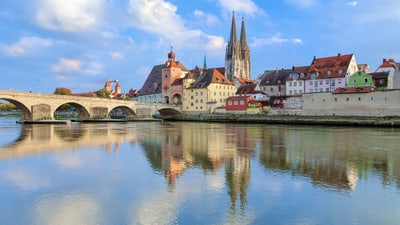 regensburg.jpg Flussblick auf mittelalterliche Stadt mit Brücke und Kirchtürmen.