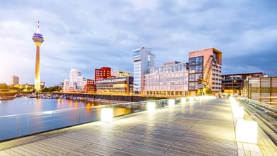 Holzsteg und beleuchtete Skyline am Abend in Düsseldorf.