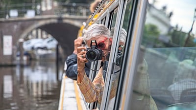 twerenbold_74837.jpg Person mit Kamera lehnt sich aus Bootsfenster.