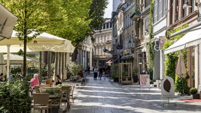Belebte Fussgängerzone mit Cafés und Geschäften.