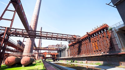 twerenbold_56240.jpg Historische Industrielandschaft mit Schornstein und Stahlstrukturen.