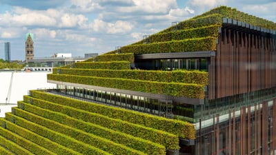 Gebäude mit terrassenförmigen grünen Pflanzen auf dem Dach in einer Stadt.