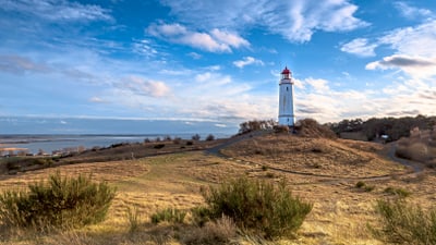 hiddensee.jpg Leuchtturm auf einem Hügel mit Blick auf das Meer.