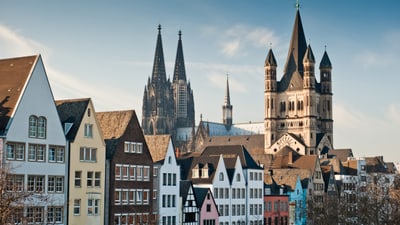 koeln-die-lebendige-metropole-am-rhein.jpg Bunte Häuserzeile und Dom in Köln bei Tageslicht.