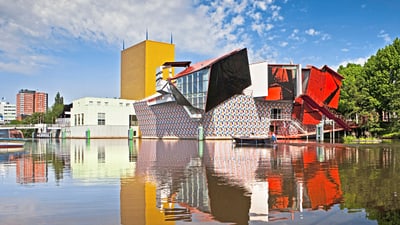 Bunte moderne Gebäude spiegeln sich in einem ruhigen Fluss.