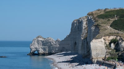 twerenbold_98268.jpg Küstenlandschaft mit Felsen und Strand, Menschen geniessen das Meer.