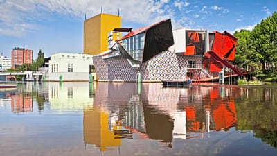 twerenbold_73436.jpg Bunte moderne Gebäude spiegeln sich in einem ruhigen Fluss.