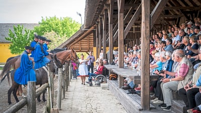 twerenbold_47662.jpg Reitvorführung vor sitzendem Publikum unter überdachtem Holzstand.