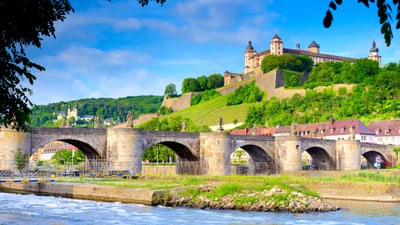 eine-fluss-trilogie-mit-unzaehligen-facetten-3.jpg Historische Brücke und Festung über Fluss in Würzburg.