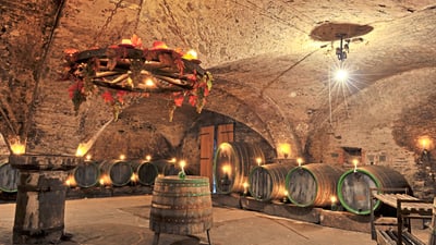 twerenbold_72921.jpg Historischer Weinkeller mit Fässern und Kronleuchter.