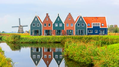 volendam.jpg Reihenhäuser und Windmühle am Kanal in grüner Landschaft.