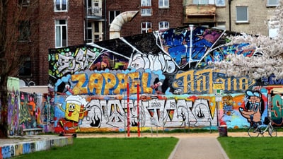 urban-art-tour-koeln.jpg Wand mit buntem Graffiti in urbaner Umgebung.