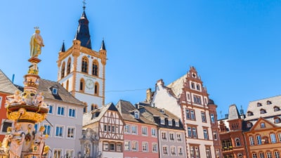 twerenbold_56292.jpg Historische Gebäude und ein verzierter Brunnen unter klarem Himmel.