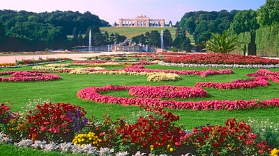 twerenbold_65675.jpg Gartenlandschaft mit Blumenbeeten und historischem Gebäude im Hintergrund.
