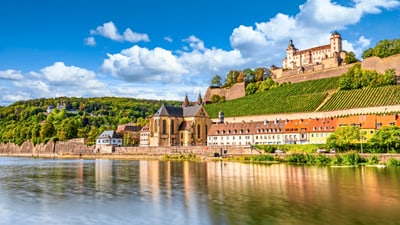 Blick auf Fluss, historische Gebäude und Festung auf Hügel.