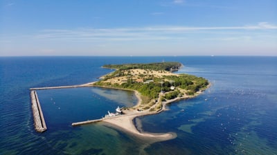 Luftaufnahme einer kleinen Insel mit grünem Bewuchs im Meer.