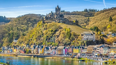 twerenbold_58151.jpg Burg auf Hügel über malerischer Stadt am Flussufer.