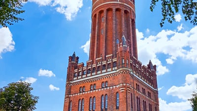 twerenbold_78084.jpg Historischer Wasserturm aus rotem Backstein vor blauem Himmel.