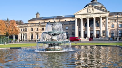 twerenbold_77983.jpg Brunnen vor dem historischen Gebäude mit Kuppel und Säulen.