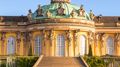 Fassade des Schlosses Sanssouci mit Kuppeldach und Treppen.
