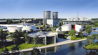 647820.jpg Luftaufnahme von modernen Gebäuden und einem Teich in einer grünen Landschaft.