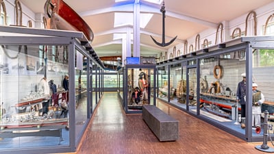 Schifffahrtsmuseum mit Booten und maritimen Exponaten in Vitrinen.