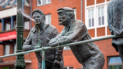 emden.jpg Bronzefiguren zweier Männer, einer spuckt Wasser.
