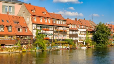 twerenbold_85481.jpg Fachwerkhäuser mit roten Dächern am Flussufer.