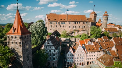 Luftbild einer mittelalterlichen Burg und Stadt mit roten Ziegeldächern.