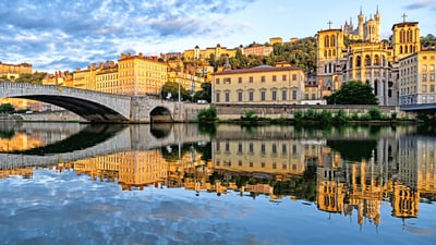 lyon.jpg Fluss mit Brücke und historischer Stadtkulisse im Sonnenlicht.