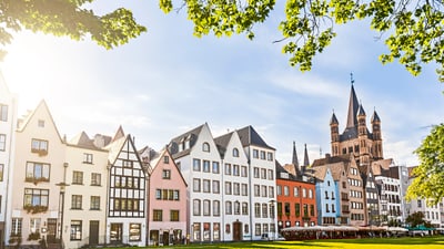 koeln.jpg Bunte Häuserreihe und Kirche am sonnigen Tag.
