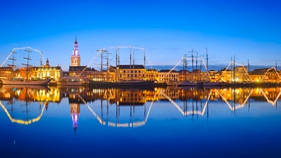 twerenbold_51492.jpg Beleuchtete Schiffe und Gebäude bei Nacht, spiegeln sich im Wasser.