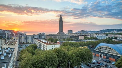 twerenbold_52062.jpg Stadtpanorama bei Sonnenuntergang mit Turm und Bäumen.