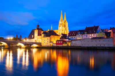 regensburg.jpg Abendansicht der beleuchteten Stadt mit Kirche und Flussreflektion.